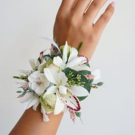White floral wrist corsage with pink accents on a person's wrist