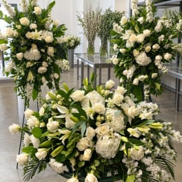 Large white floral funeral arrangements with roses and lilies in a room