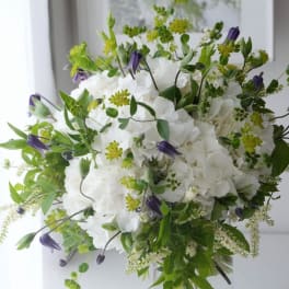 White hydrangea bouquet with purple bell-shaped flowers and green accents