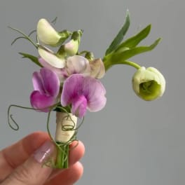 Small purple and white boutonniere with a hand holding it