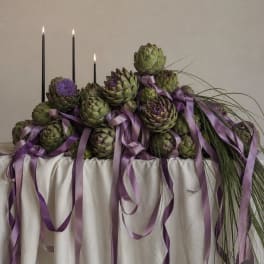 Artichoke centerpiece with purple ribbons and tall black candles