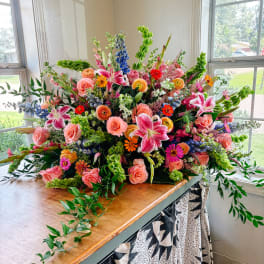 Large mixed bouquet with pink roses, lilies, and blue flowers on a table