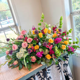 Large mixed floral arrangement with pink and yellow roses in a low container