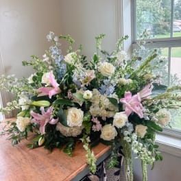 Large pastel floral arrangement with white roses, pink lilies, and blue flowers