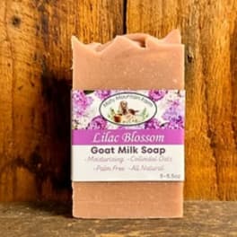Bar of lilac blossom goat milk soap with a paper label