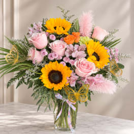Bouquet of sunflowers and pink roses in a clear glass vase