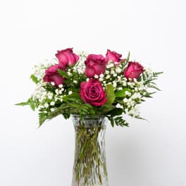 Pink roses arranged in a clear glass vase with white filler flowers