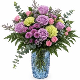 Lavender and pink roses with purple mums in a blue glass vase