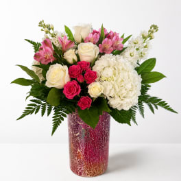 Pink and white flower arrangement in a tall patterned vase