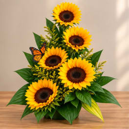 Sunflower arrangement with five blooms and a butterfly accent in a low container