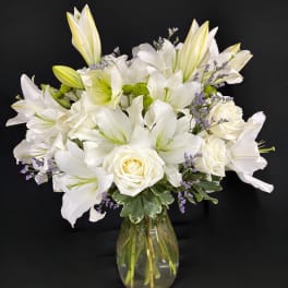 White lilies and roses arranged in a glass vase