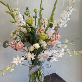 Tall mixed bouquet in a clear glass vase with white, pink, and green blooms