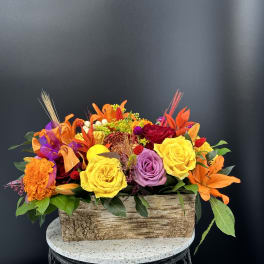 Bright mixed flower arrangement in a rustic rectangular wooden container