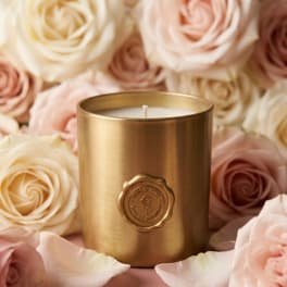 Gold candle surrounded by blush and cream roses