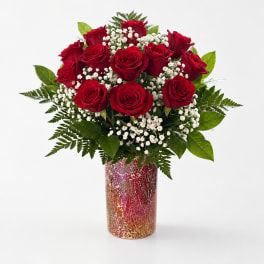 Red roses arranged in a patterned vase with white filler flowers