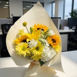 Bouquet of yellow sunflowers and white flowers wrapped in cream paper