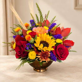 Mixed bouquet with sunflowers, red roses, and colorful mums in a bronze bowl vase