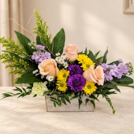 Mixed flower arrangement in a rectangular vase with roses and daisies