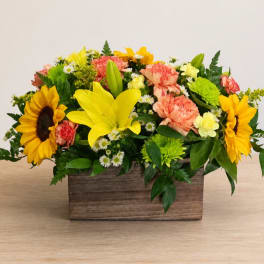 Mixed bouquet in a wooden box with sunflowers, lilies, and carnations