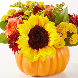 Sunflower and mixed flower arrangement in an orange pumpkin container
