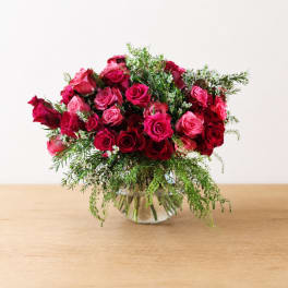Pink and red roses arranged in a clear glass vase