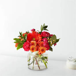 Orange and pink mixed bouquet in a clear glass vase