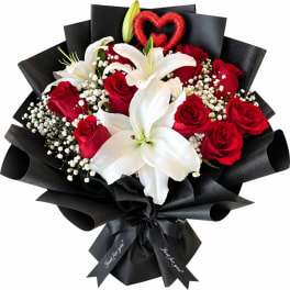 Bouquet of red roses and white lilies wrapped in black paper
