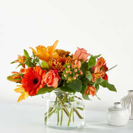 Orange and peach mixed bouquet in a clear glass vase