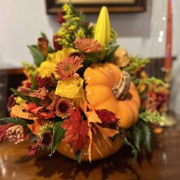 Autumn floral arrangement in a pumpkin with yellow, orange, and red blooms