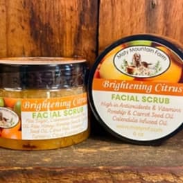 Two jars of brightening citrus facial scrub on a wooden surface.