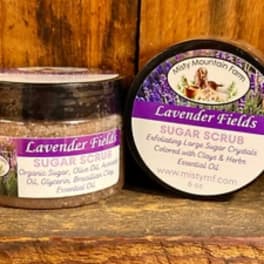 Two lavender sugar scrub jars on a wooden surface.