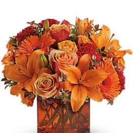Orange and red mixed bouquet in a square glass vase