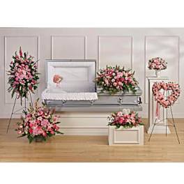 Funeral casket surrounded by pink floral sprays and wreaths