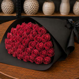 Bouquet of red roses wrapped in black paper with a ribbon