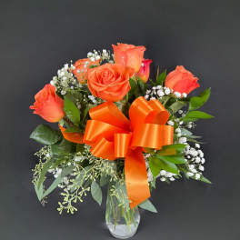Orange rose bouquet in a clear glass vase with an orange ribbon