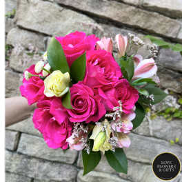 Hand-tied bouquet of hot pink roses with pale yellow roses and pink alstroemeria.
