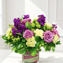Pink roses and purple flowers arranged in a square glass vase