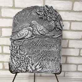 Stone memorial plaque with two birds and floral relief, reading "Always in our Hearts"