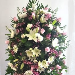 Tall standing floral spray with pink and white flowers on a black easel