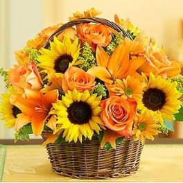 Basket of orange roses, sunflowers, and lilies