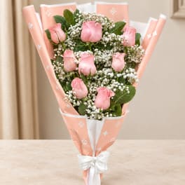 Pink rose bouquet wrapped in peach paper with a white bow