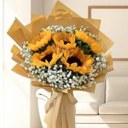 Bouquet of sunflowers wrapped in tan paper with white filler flowers