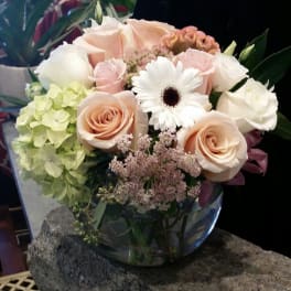 Bouquet of pale roses, hydrangea, and a white gerbera daisy in a glass vase