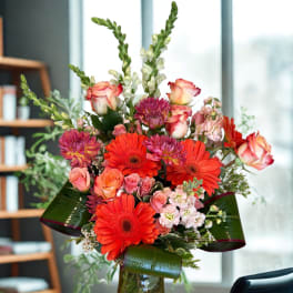 Bouquet of orange gerbera daisies and pink roses in a glass vase