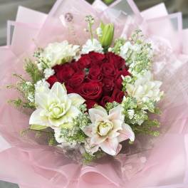 Bouquet of red roses and white lilies wrapped in pink paper