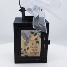 Black lantern with a white bow and memorial plaque reading "In the arms of an Angel"