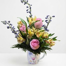 Pink roses and yellow alstroemeria in a floral mug vase