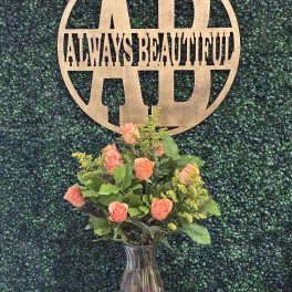 Coral roses in a clear glass vase with yellow filler flowers