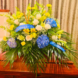 Large mixed flower arrangement with blue ribbons and a "Husband" sash