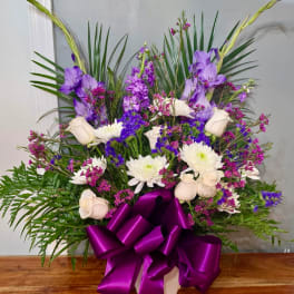 Purple and white floral arrangement with a large purple ribbon bow